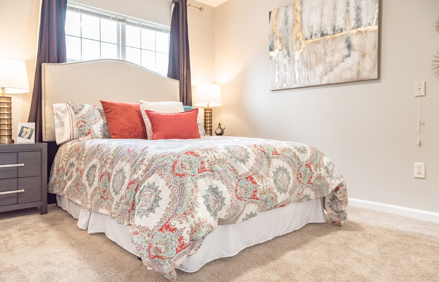 Furnished bedroom with bed, seating area, and soft lighting.
