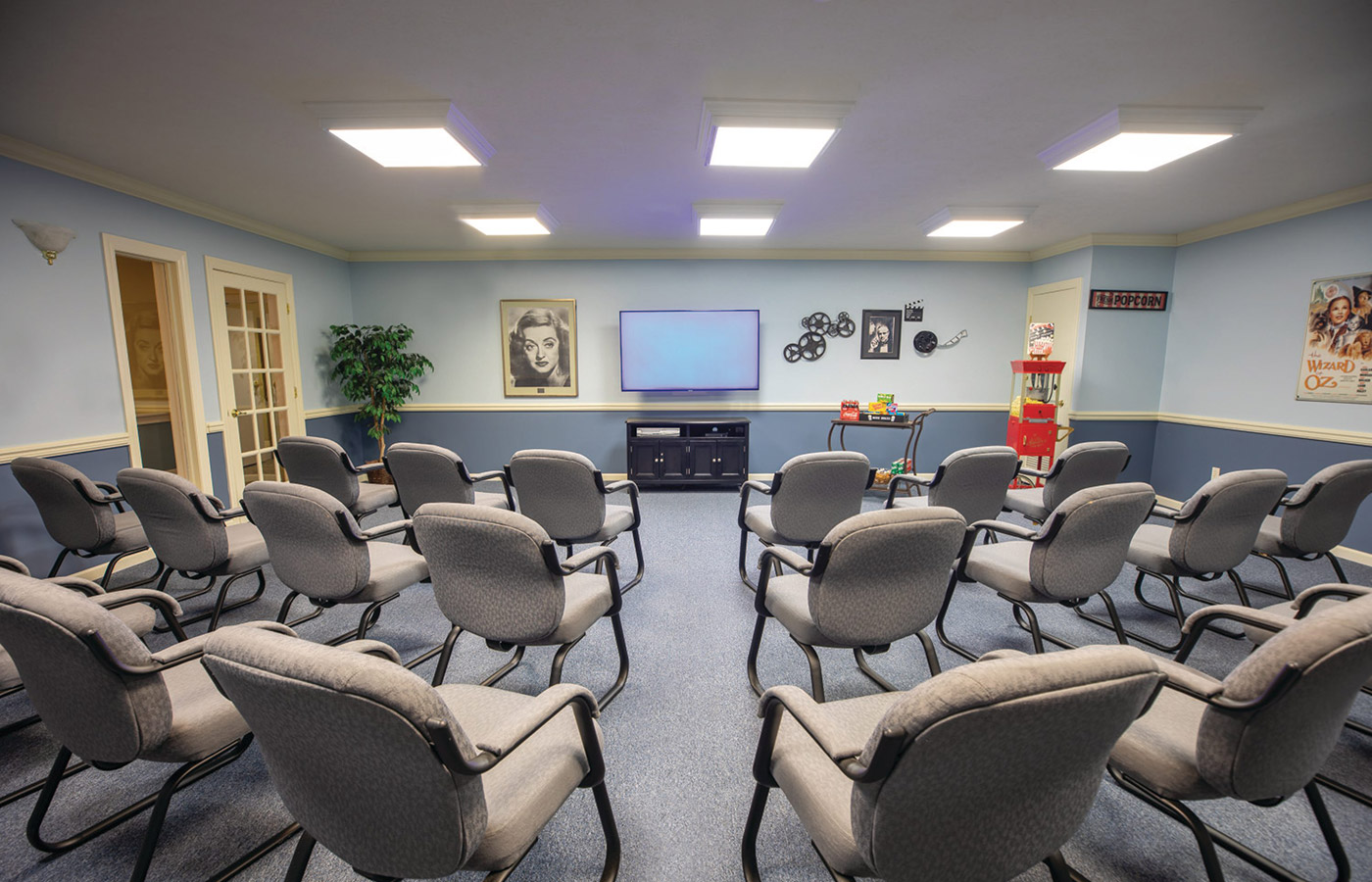Theater room with television screen and chairs.
