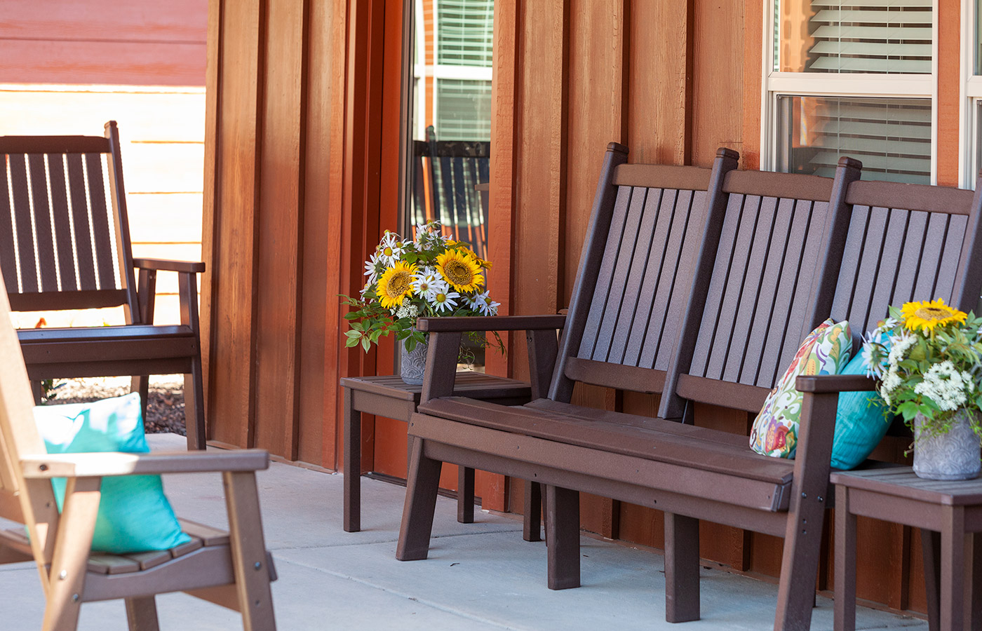 Brown bench with pillows and flowers.