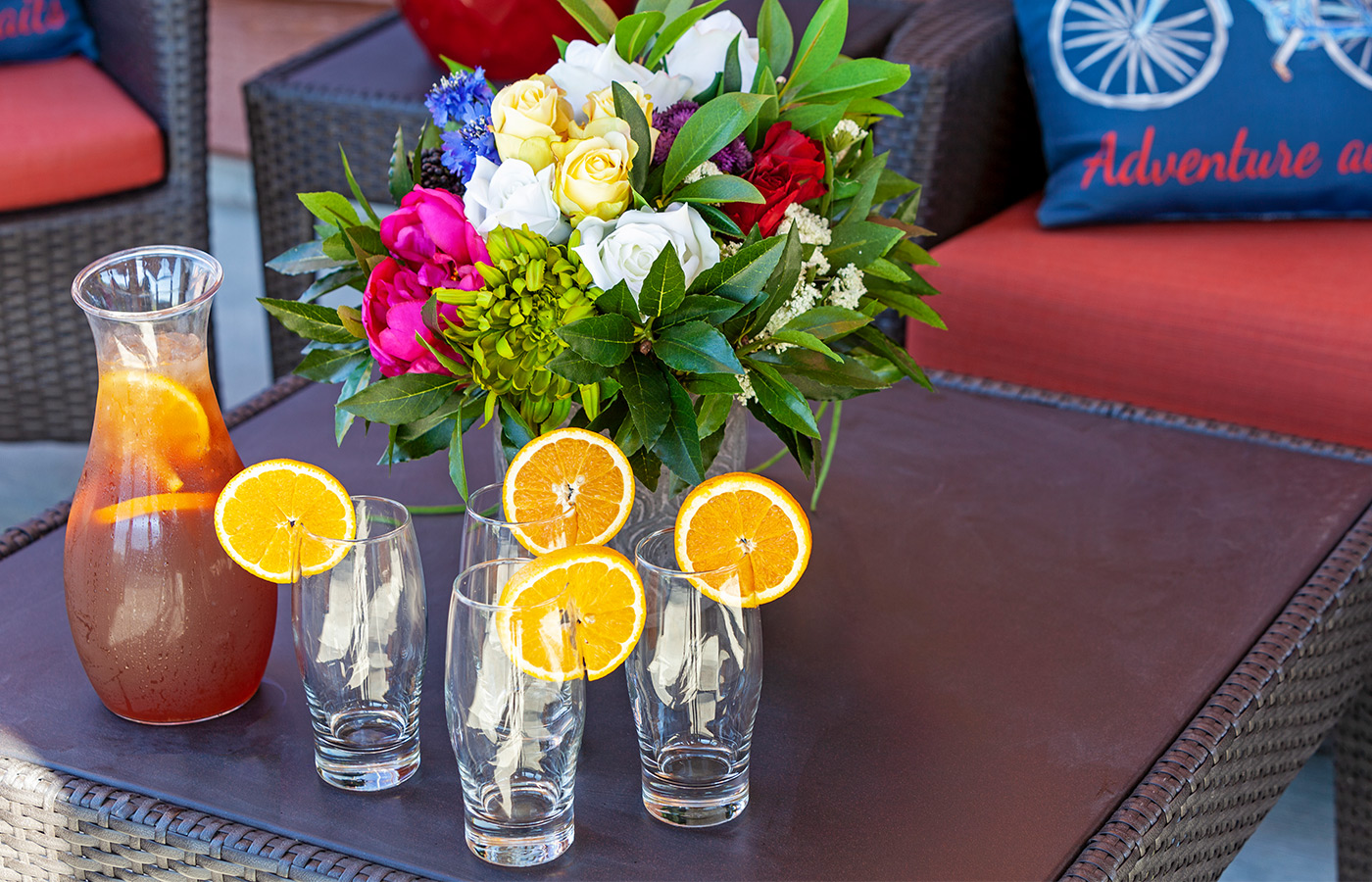 Pitcher of tea with glasses and flowers.