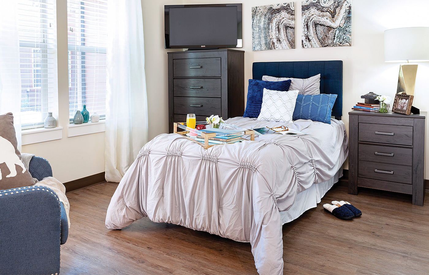 Furnished bedroom with bed, window, and dresser.