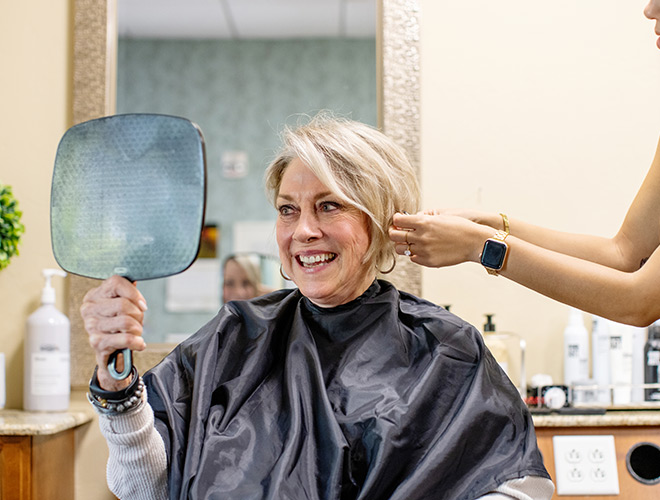 A resident looks into mirror while they get their hair styled.