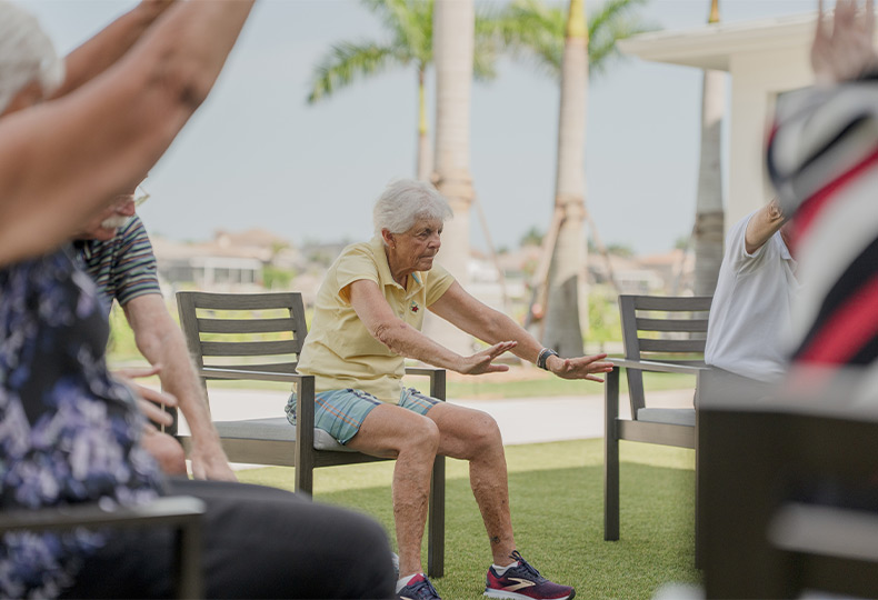 A group of people outside doing seated yoga.