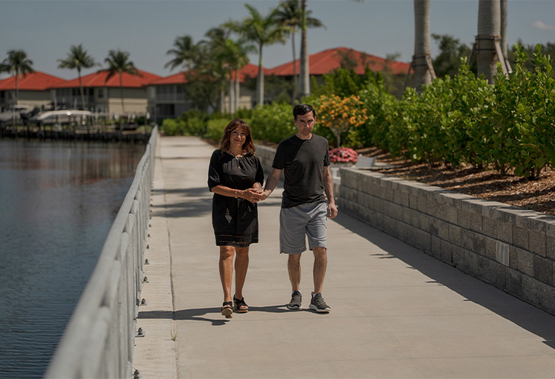 Two people walking by the water.