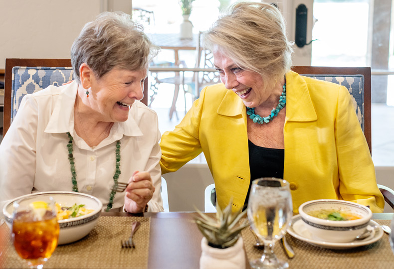 Two residents are eating together in a dining area.