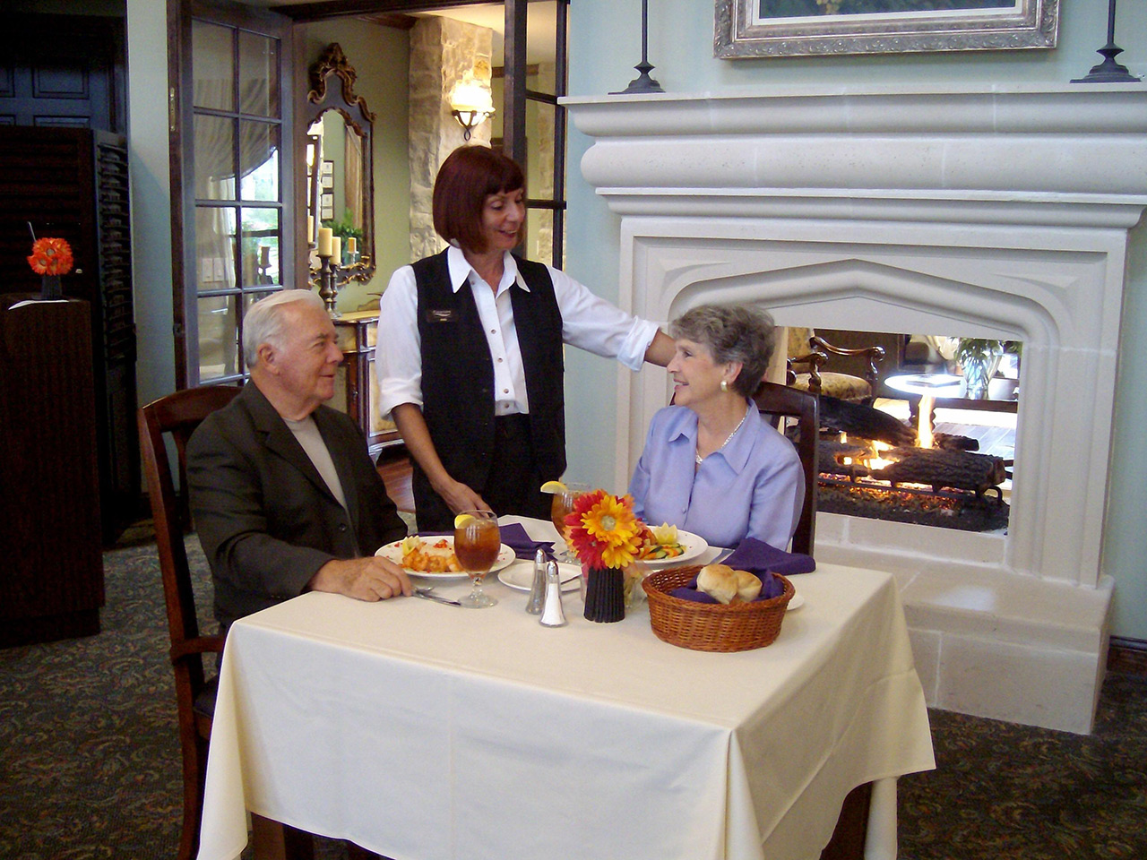 Couple enjoy dinner by the fireplace.