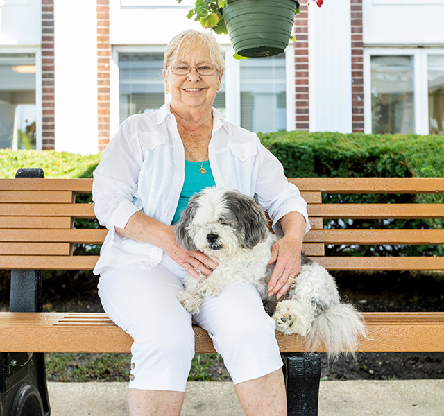 A person sitting on a bench with their dog.