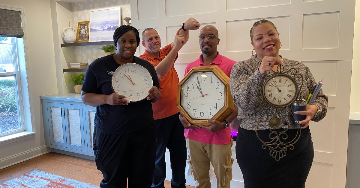 A group of people holding clocks.