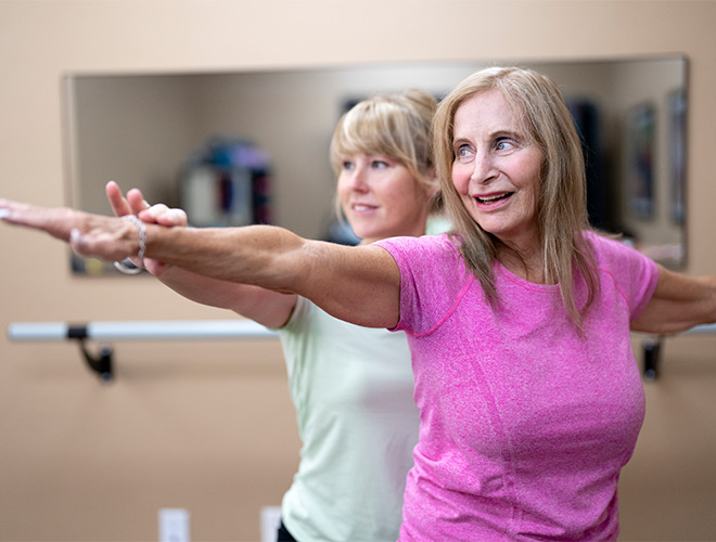A person helping another stretch.
