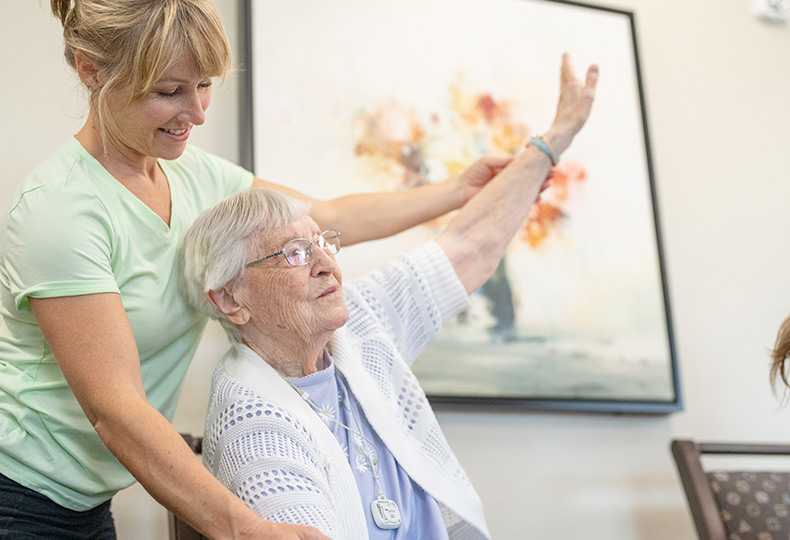A caregiver helps a resident stretch their arm. 