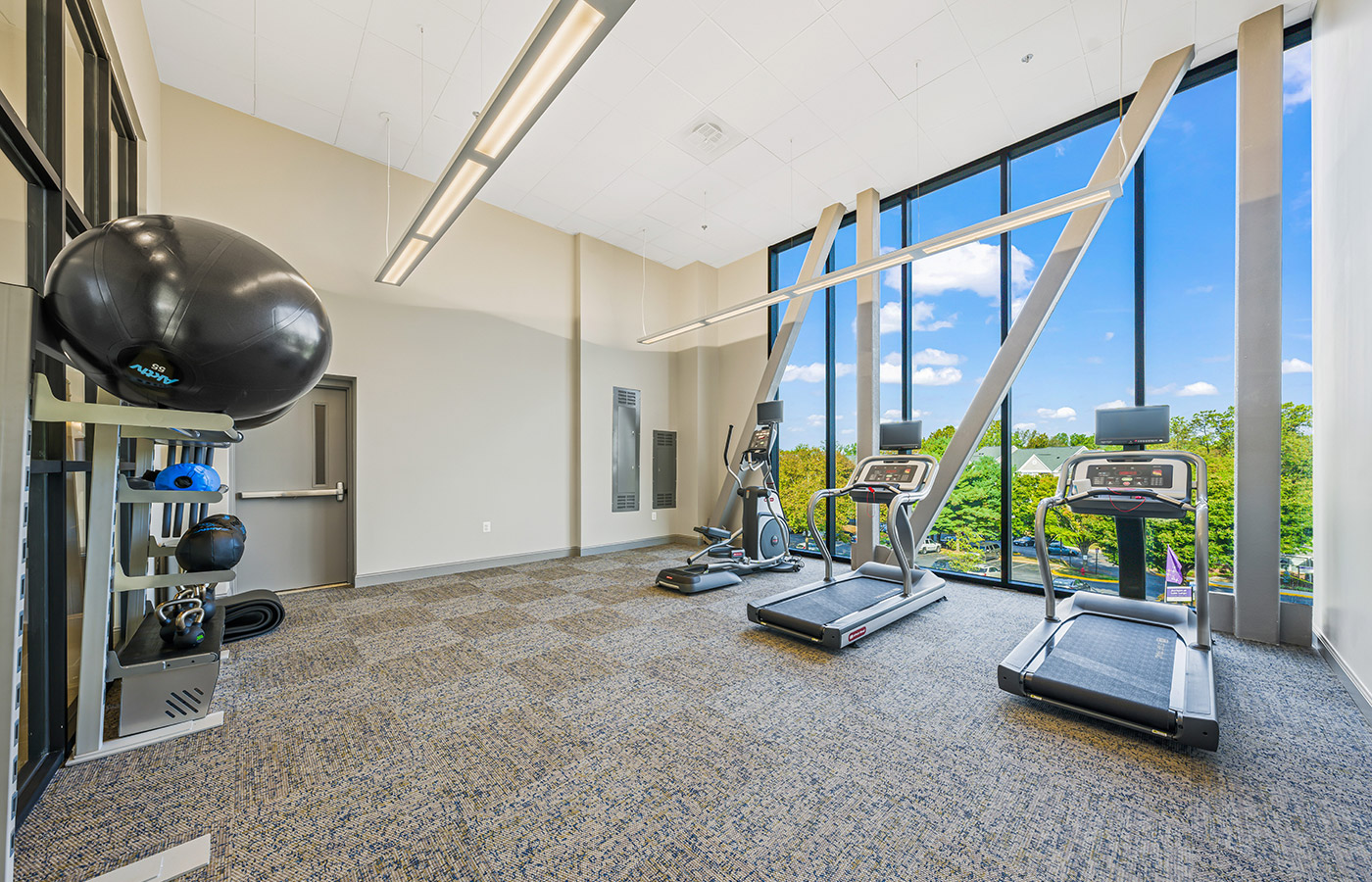 fitness area with various machines and large long windows