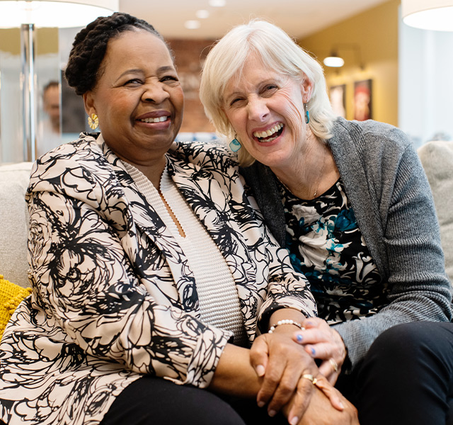 Two people laughing on a couch.