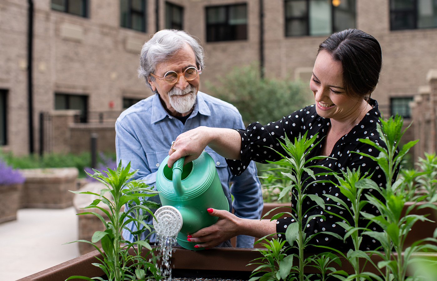 A person helping another water plants.