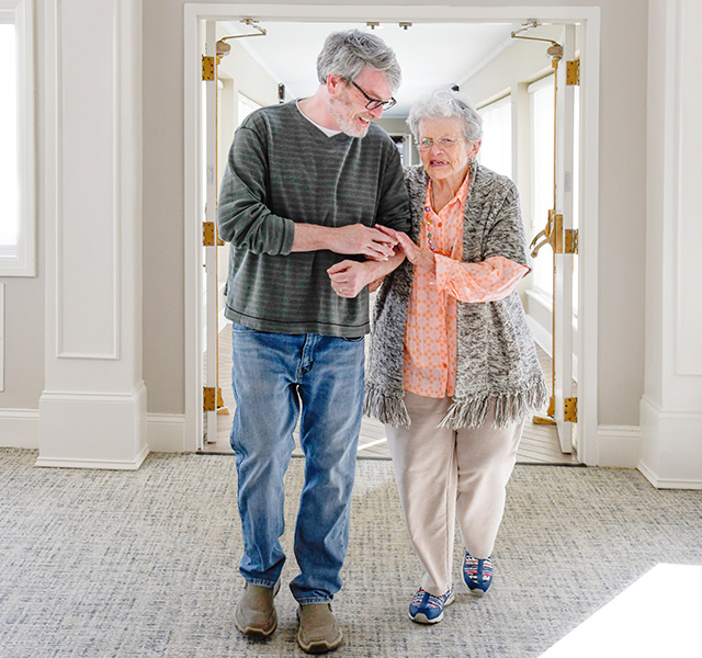 A person helping a resident walking.