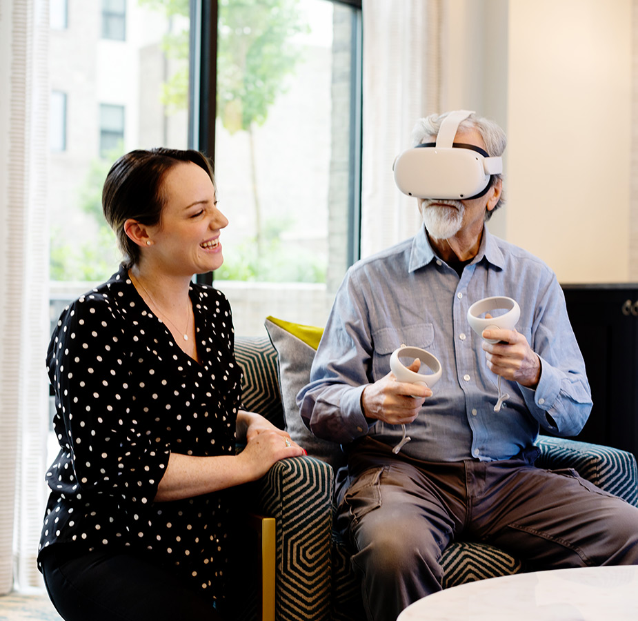 A naya caregiver helping a resident with a VR headset on.