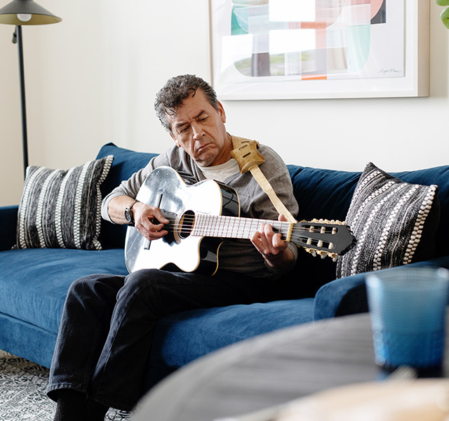A person on the couch playing guitar.