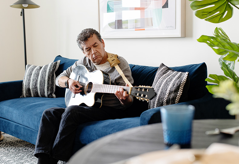 A person sitting on the couch playing guitar.