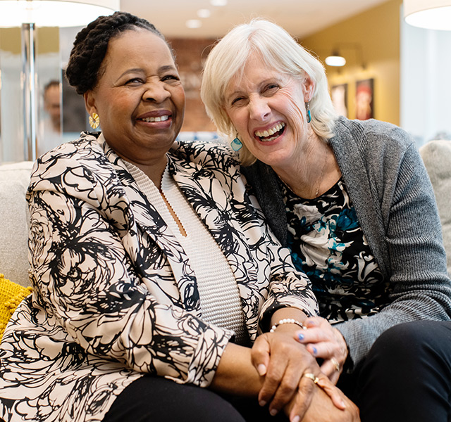 Two friends sitting on the couch laughing.