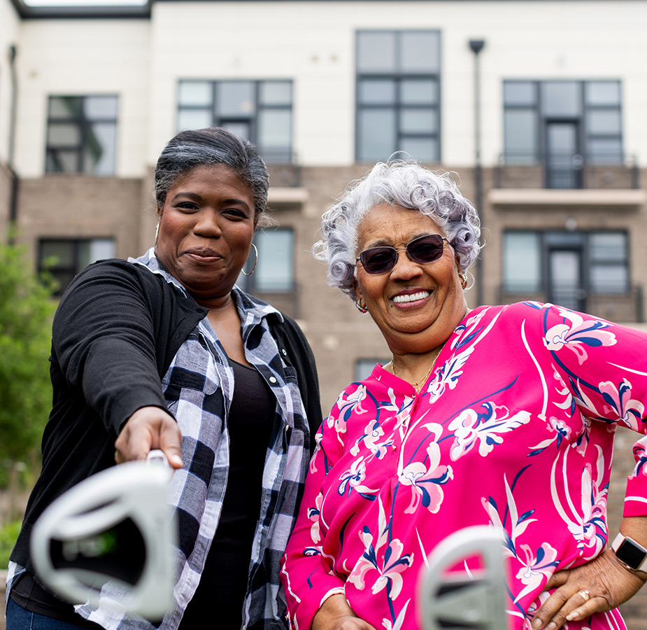 Two people holding golf clubs out.