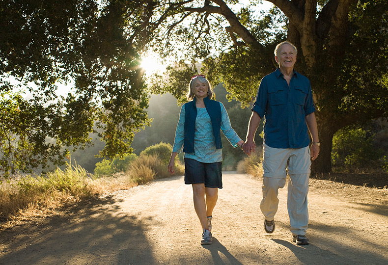 Two residents holding hands walking outside.