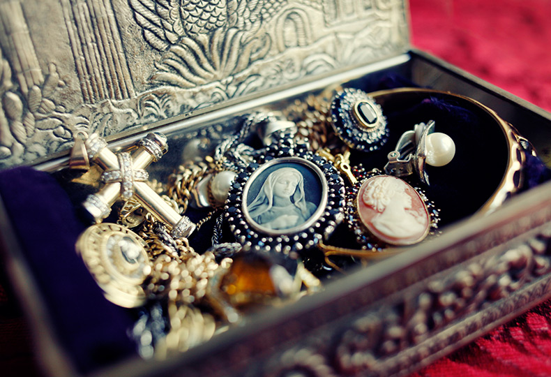 An antique jewelry box with cameos and other necklaces in it.