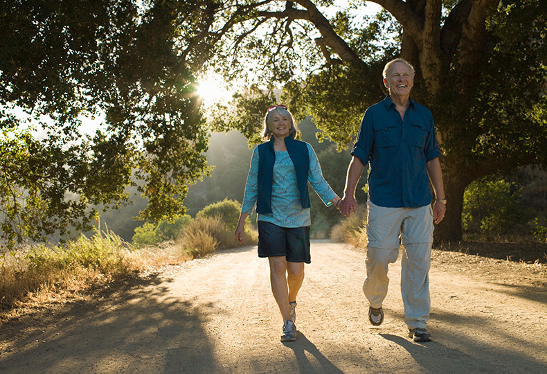 Two people walking on a trail outside.