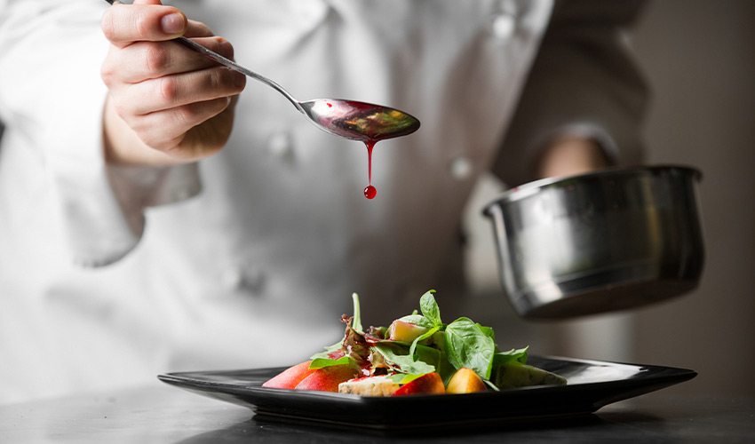 A chef putting food on a plate.