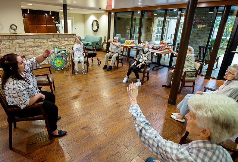 A group fitness class with a bunch of residents seated.