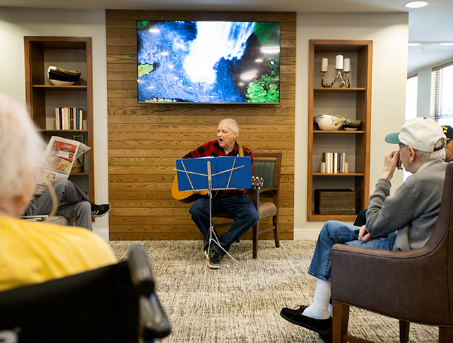 A person playing the guitar and singing for residents.