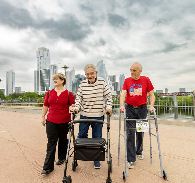 Two residents and a caregiver walking on a bridge.
