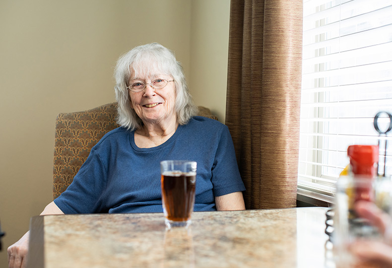 A resident sitting at a table and smiling.