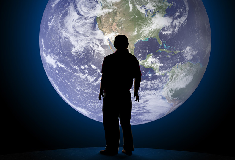 A person standing in from of an image of Earth.