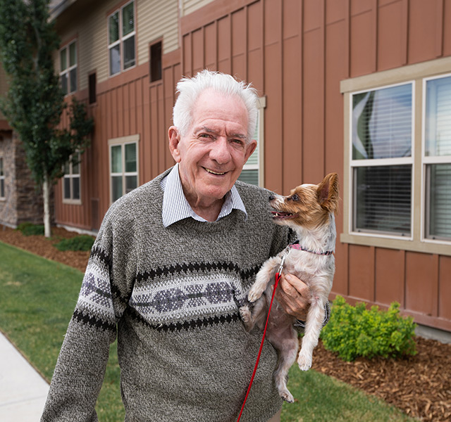 A person holding their dog outside.