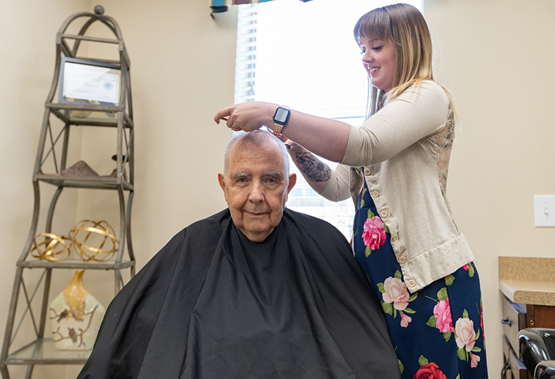 A resident is having their haircut in the salon.