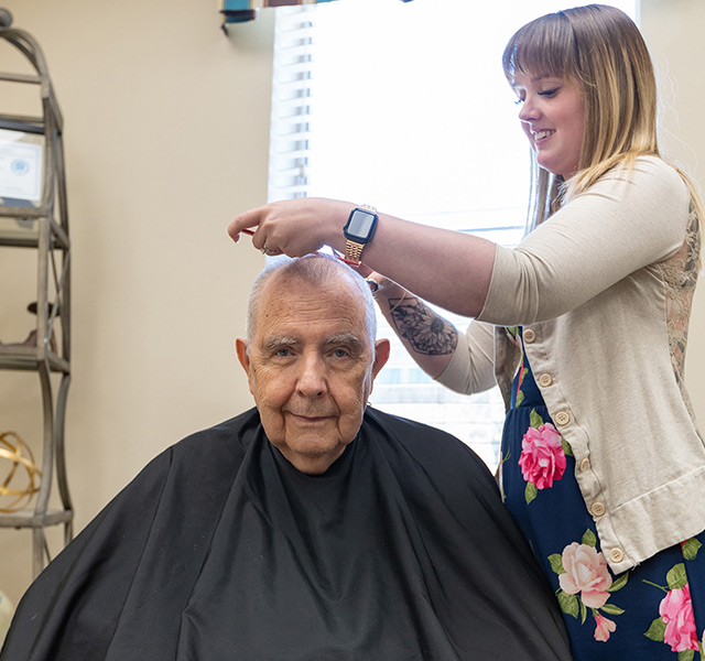 A resident is having their haircut in the salon.