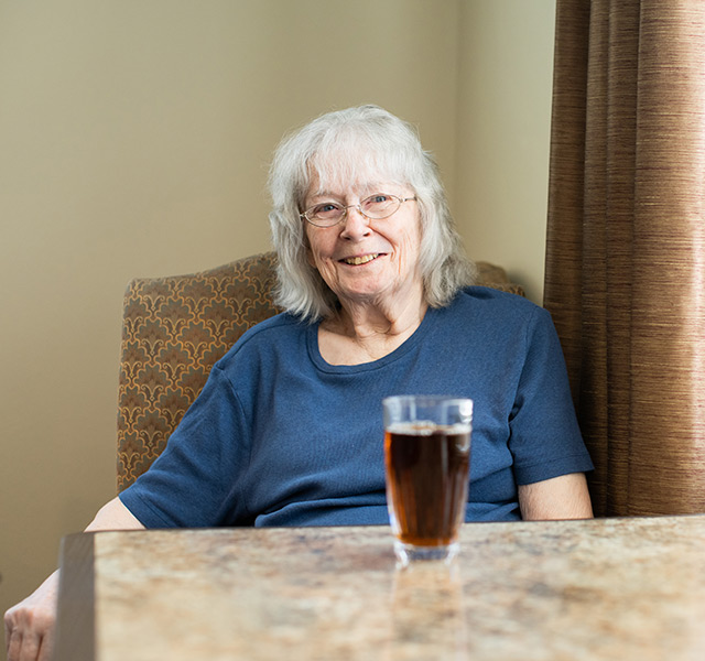 A resident sitting at a table and smiling.