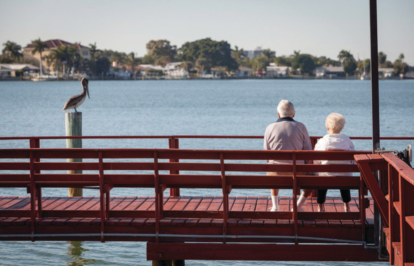 Elderly couple sitting on the pier looking out towards the bay