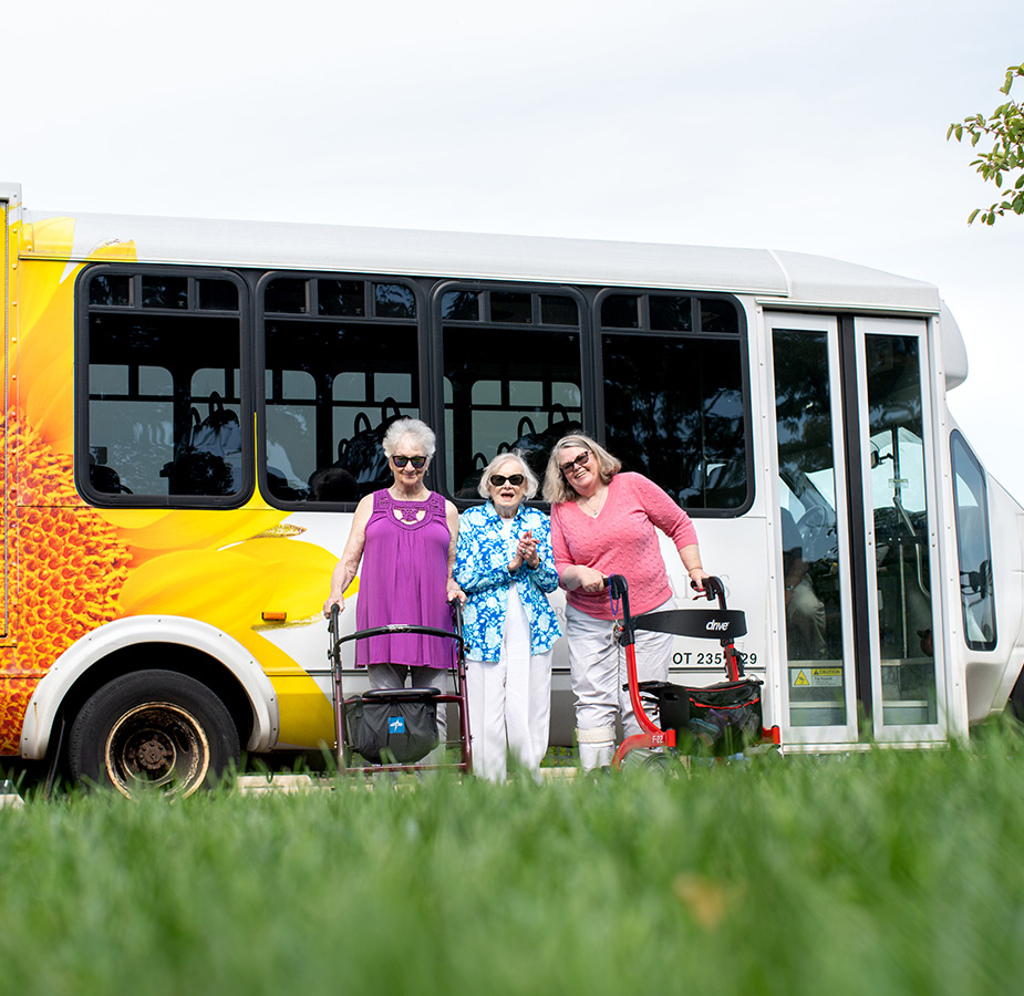 Three ladies with walkers standing in front of the Watermark bus.