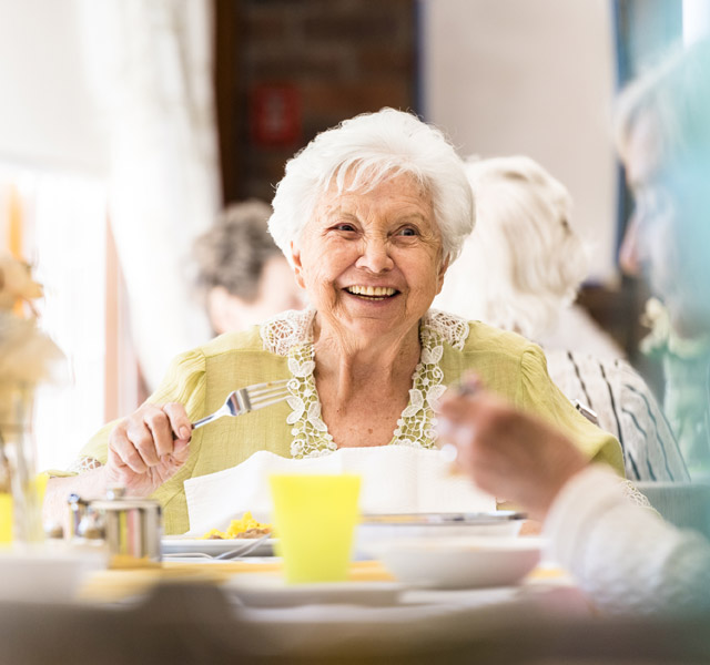 A resident having dinner and laughing.