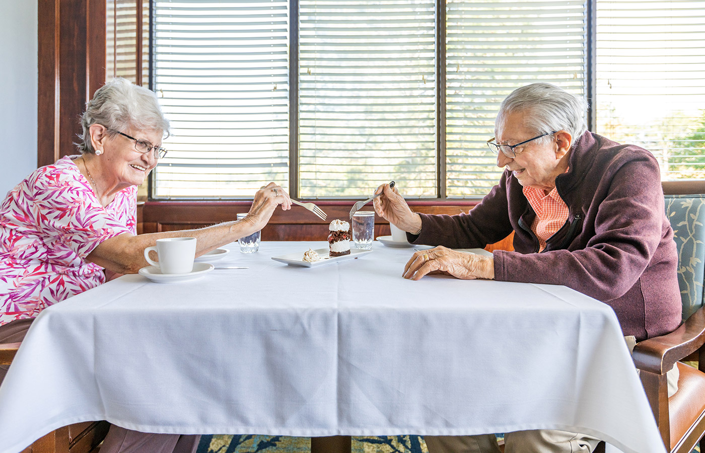 Two residents are sharing a dessert together with forks in hand.