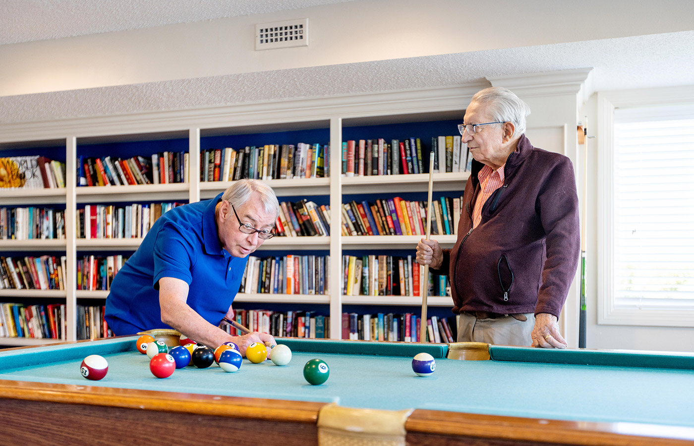 Two residents are playing a game of pool.