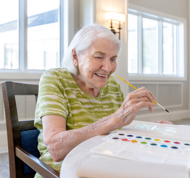A resident is painting in an art class.