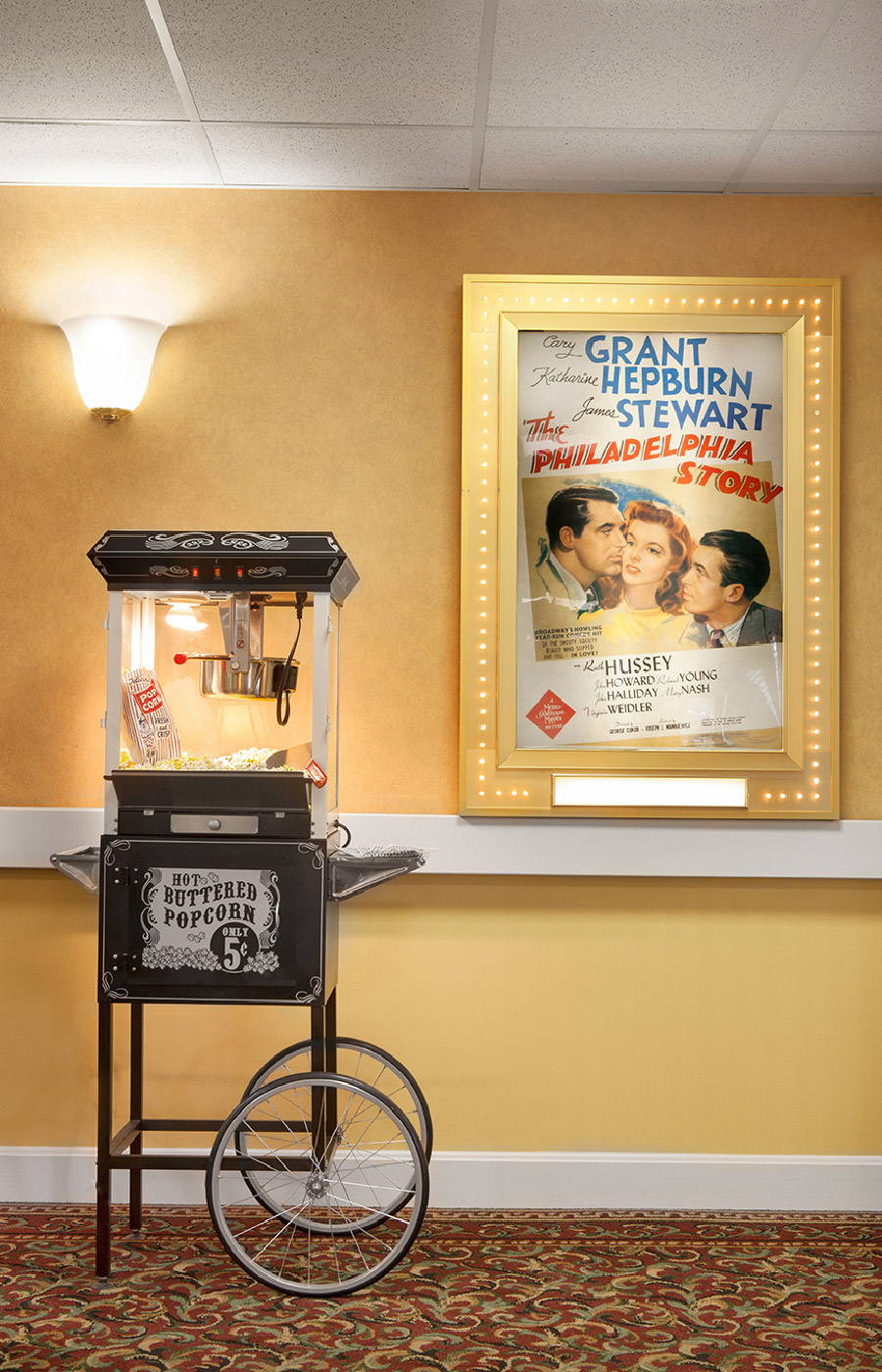A popcorn machine by a movie poster.