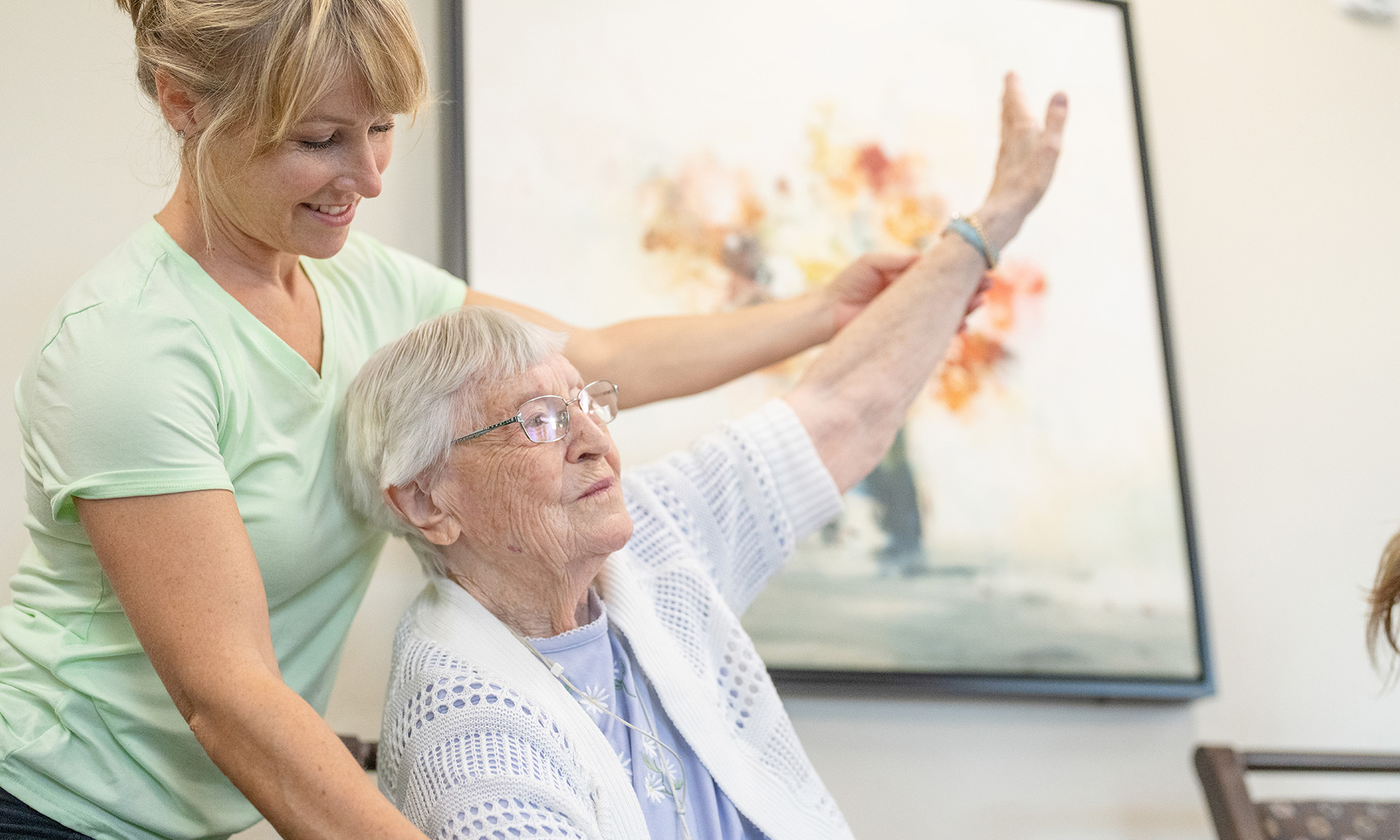 A caregiver helps a resident stretch their arm.