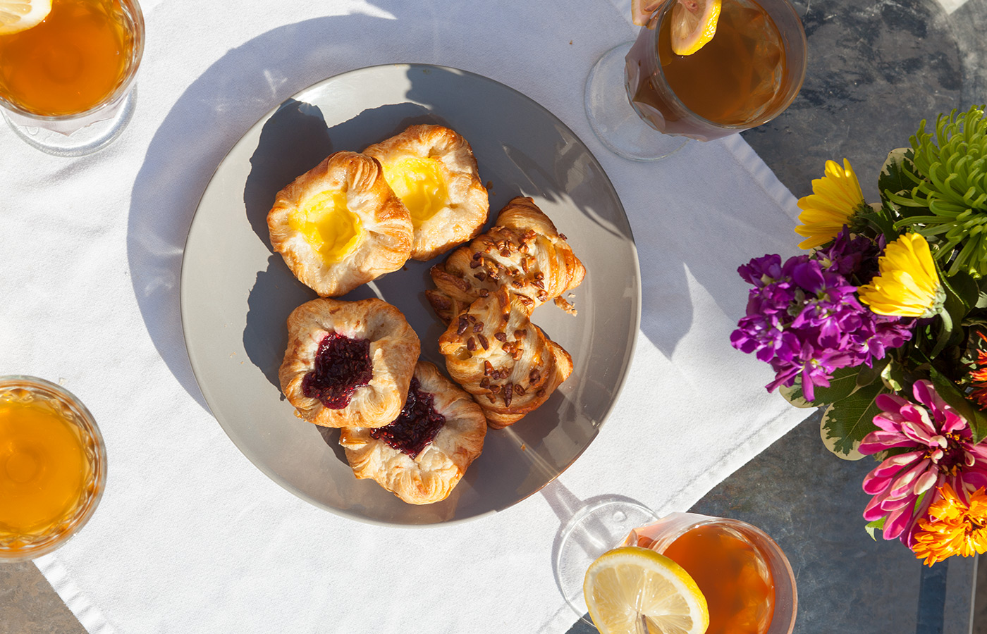table with a plate of pastries and purple and orange flowers 