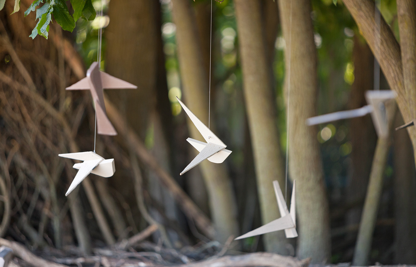Wooden birds are hanging in a garden.