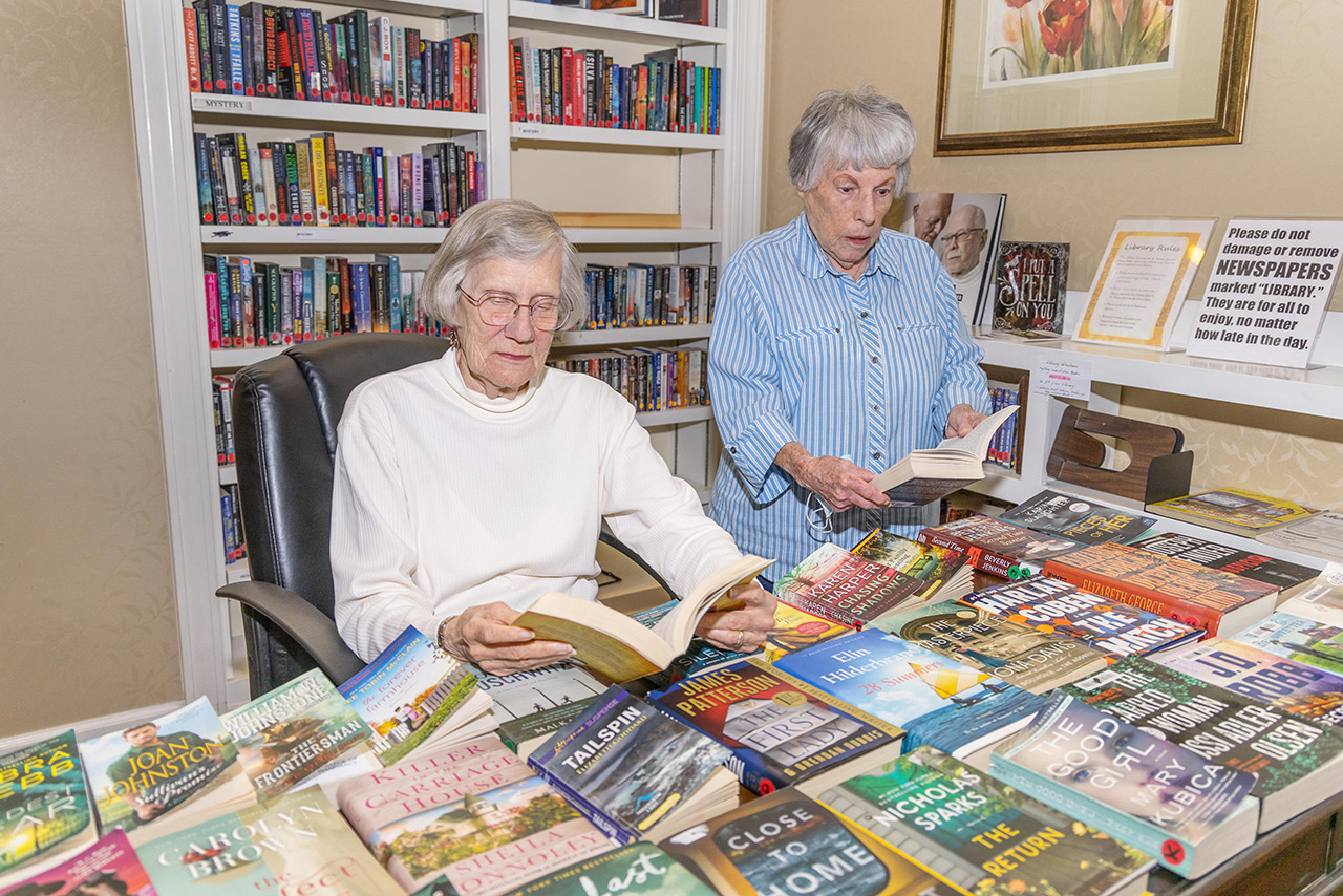 Two residents are in the library looking at books.