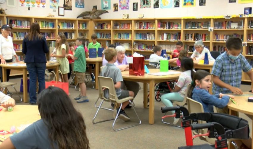 Residents from The Fountains at La Cholla are with kids in a classroom at an elementary school.