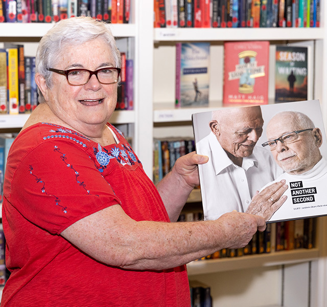 A resident is holding open a book in the library.
