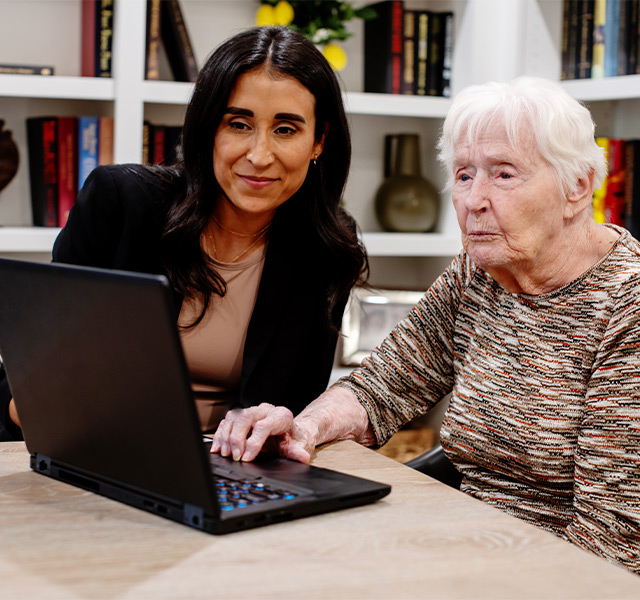 A person helping a resident on the computer.